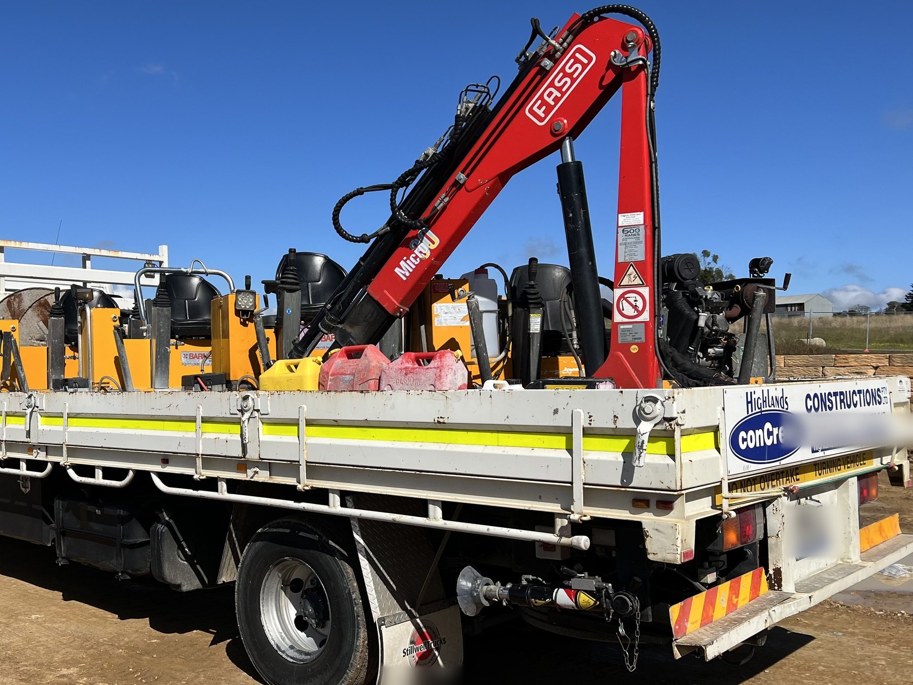Highlands crane truck loaded with ride-on power trowels and finishing equipment
