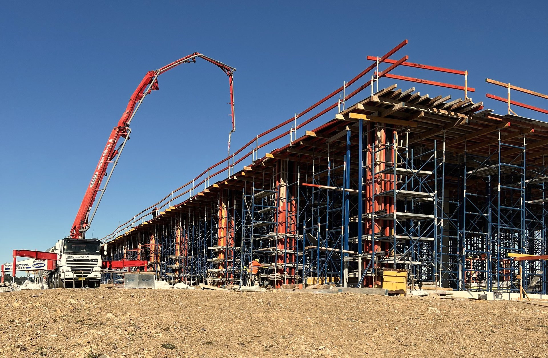 Boom pump reaching over dense falsework and suspended deck formwork on a data centre build