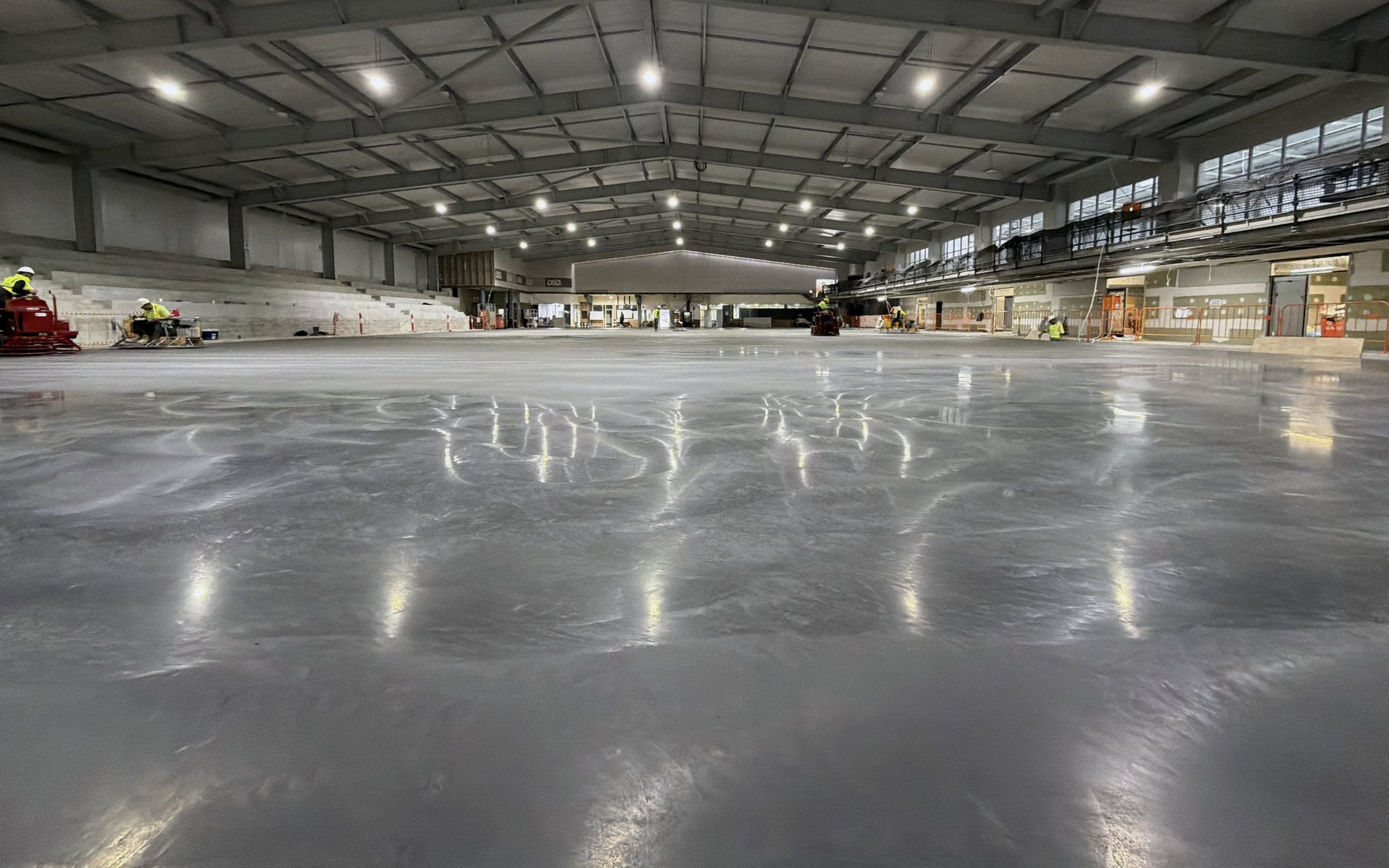 Machine-finished superflat competition ice rink slab under arena lights